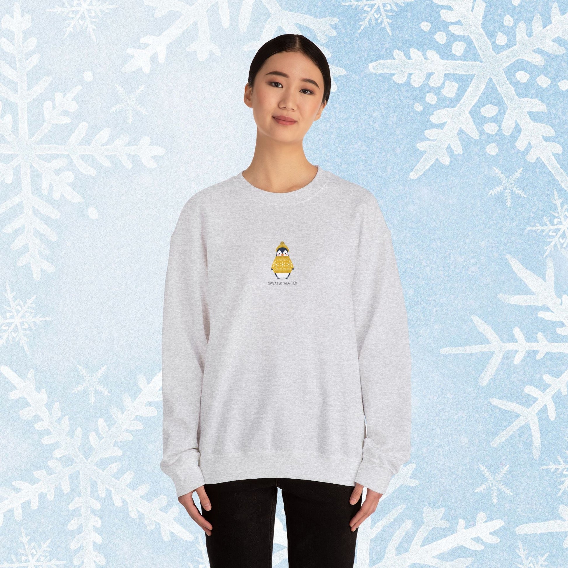 Sweater Weather Unisex Crewneck Sweatshirt - Staying Warm and Fuzzy. Small centered Penguin design wearing a yellow Sweater with text under "sweater weater"