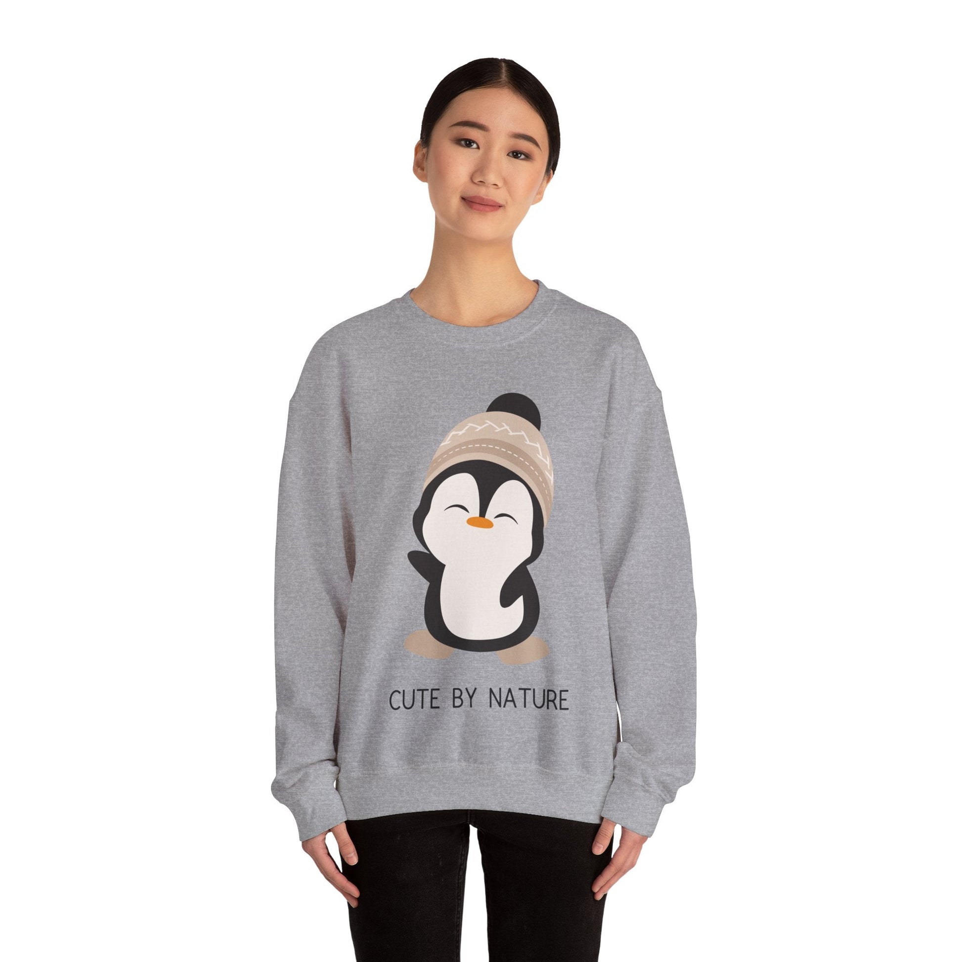 Cute Penguin Sweatshirt - Unisex Heavy Blend™ Crewneck, Cute by Nature, big cute winter penguin design, underneath a text "cute by nature"