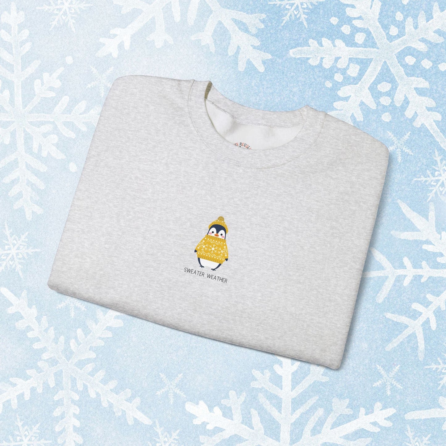 Sweater Weather Unisex Crewneck Sweatshirt - Staying Warm and Fuzzy. Small centered Penguin design wearing a yellow Sweater with text under "sweater weater"