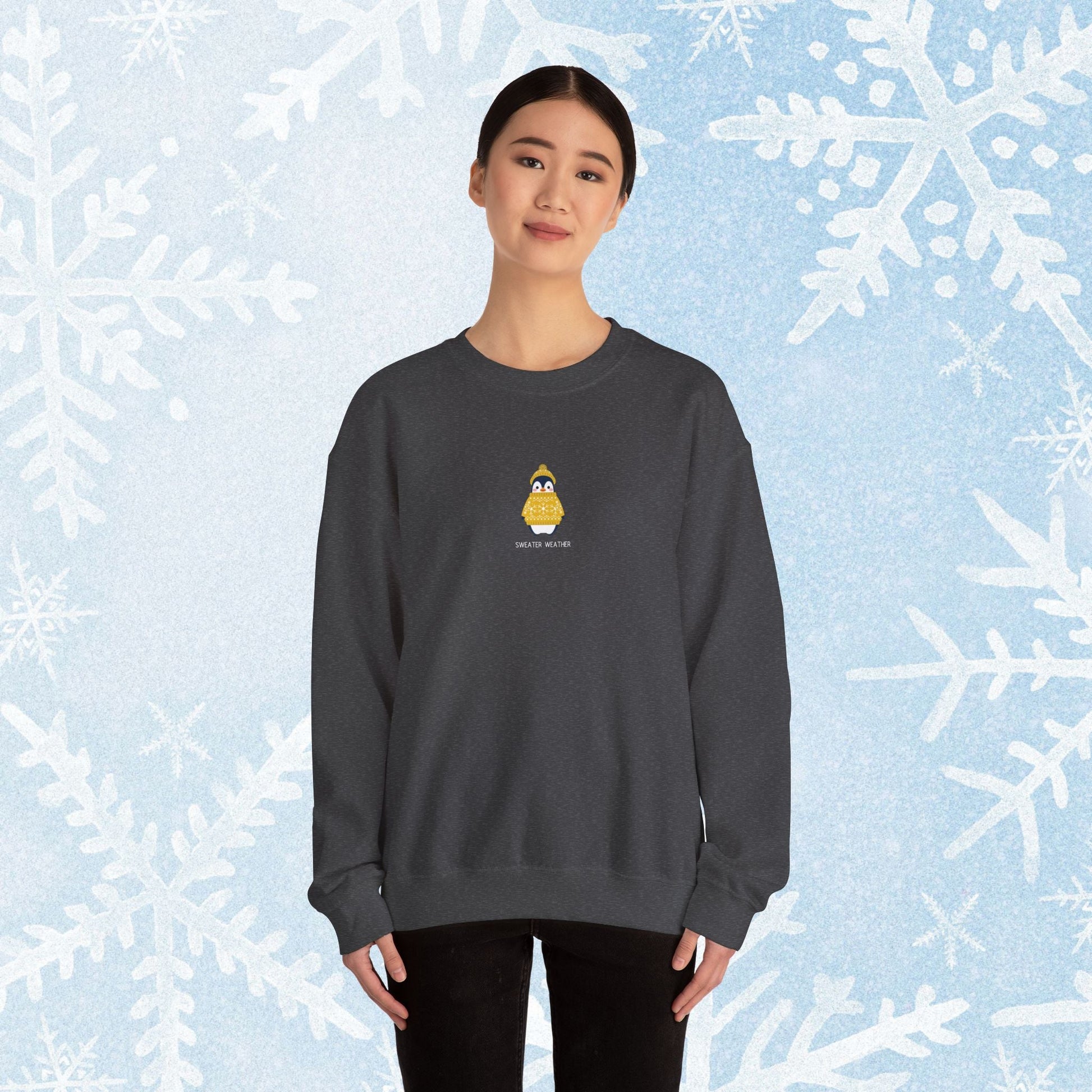 Sweater Weather Unisex Crewneck Sweatshirt - Staying Warm and Fuzzy. Small centered Penguin design wearing a yellow Sweater with text under "sweater weater"