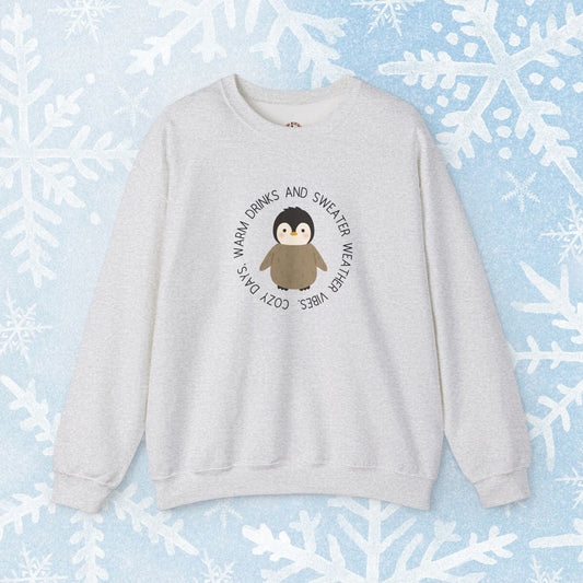 Sweater Weather Penguin Sweatshirt. cute penguin in the middle and around in a circle saying cozy days, warm drinks, and sweater weather vibes